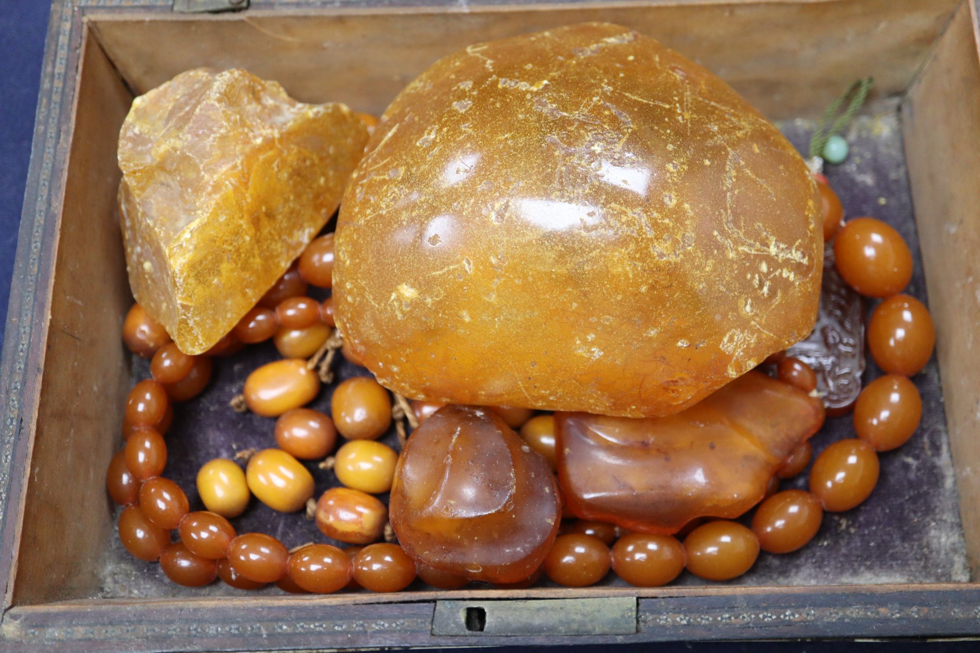 An amber necklace(a.f.) gross 85 grams, four assorted amber pebbles, 528 grams, a carved amber pendant